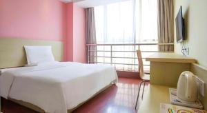 a bedroom with a white bed and a pink wall at 7 Days Inn Shaoguan Lechang in Shaoguan
