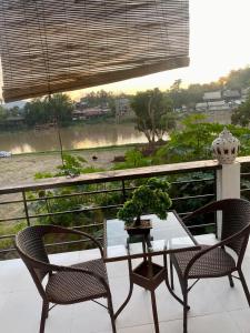 a table and chairs on a balcony with a view of a river at Meet Sunset Villa Luang Prabang in Luang Prabang