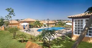 a pool with chairs and umbrellas in a yard at Vila Real Hotel in Jaú