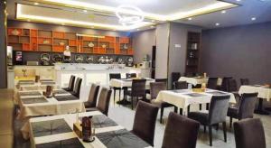 a restaurant with tables and chairs and a kitchen at Vienna Hotel Tongliao Ke'erqin in Tongliao