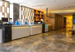 a group of people standing at a counter in a lobby at Echarm Hotel Guilin Zhongshan Zhong Road Liangjiang Sihu in Guilin
