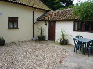 uma mesa e cadeiras em frente a uma casa em Granary Cottage em Hardwick