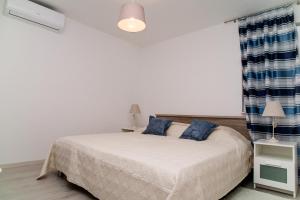 a bedroom with a bed with blue pillows at Apartment Ema in Rogoznica +31 photos