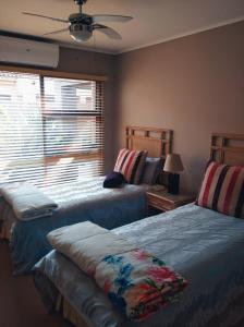 a bedroom with two beds and a window with a fan at Pecanwood Haven Hartbeesport Dam in Hartbeespoort +56 photos