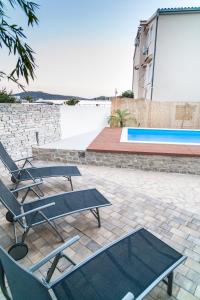 a couple of chairs and a table and a pool at Apartment Ema in Rogoznica