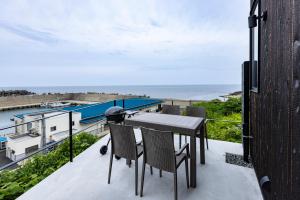 a balcony with a table and chairs and the ocean at Cottage TAIZA in Kyotango