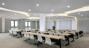 a conference room with tables and chairs and a screen at Vienna Hotel Fuzhou Changle Shouzhan Hangcheng Metro Station in Fuzhou