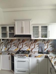 une cuisine avec des armoires blanches et un comptoir en marbre dans l'établissement Rose Apartment, à Kadawata