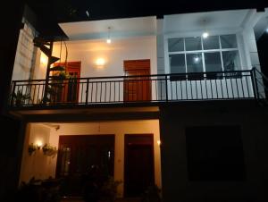 une maison avec un balcon éclairé la nuit dans l'établissement Rose Apartment, à Kadawata