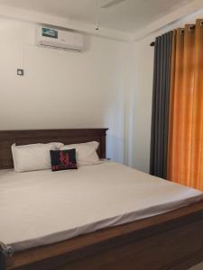 - une chambre avec un grand lit et un rideau orange dans l'établissement Rose Apartment, à Kadawata