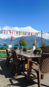a wooden table and chairs with mountains in the background at Munsyari camping zone & tracking snow hill in Munsyari