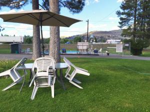 a table and chairs with an umbrella in the grass at Evergreen Motel in Princeton