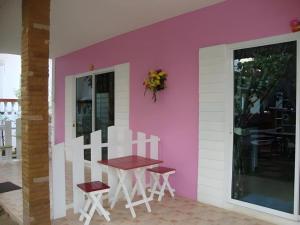 a table and chairs in front of a pink wall at Baan Gon Chompu in Ratchaburi