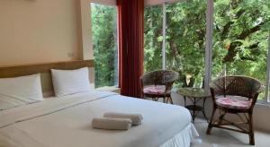 a bedroom with a bed with two chairs and a large window at Magic House Hostel in Hua Hin