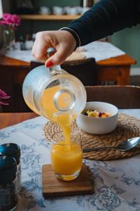 una persona vertiendo zumo de naranja en un vaso en Harewood Lodge, en East London