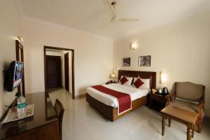 a hotel room with a bed and a chair at Bhasuri Inn Guruvayoor in Guruvāyūr