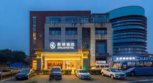 a building with cars parked in a parking lot at Junlai Hotel Pudong Airport Shanghai in Shanghai