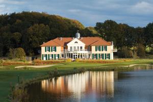 una gran casa blanca en un campo de golf con un estanque en Castello Apartments en Lüneburg