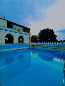 a swimming pool with a building in the background at The Shining Star 777 , Pushkar - A Beautiful Resort Nested in Nature's Lap in Pushkar