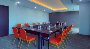 a conference room with a long table and red chairs at Java Lotus Hotel Jember in Jember +65 photos