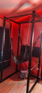 un'altalena in una stanza con una parete rossa di Le boudoir des jouissances perverses a Chasse-sur-Rhône