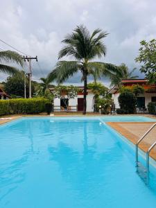 a swimming pool in front of a house with a palm tree at Lanta Nesta Resort in Ko Lanta Yai