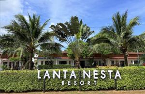a sign in front of a resort with palm trees at Lanta Nesta Resort in Ko Lanta Yai