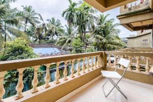 a white chair on a balcony with palm trees at ILLY's NEST in Siolim