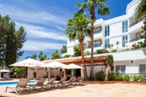 a hotel with chairs and umbrellas next to a swimming pool at Suite Hotel S'Argamassa Palace in Santa Eularia des Riu