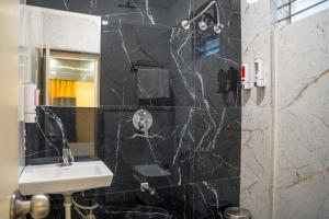 a bathroom with a sink and a black tile wall at Open Hotel by Olive - Meet Me At in Bengaluru +29 photos