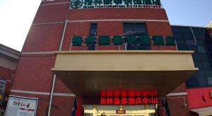 un edificio rosso con sedie verdi in cima di GreenTree Inn Shanghai Sheshan national tourist resort Express Hotel a Fenghuangshan