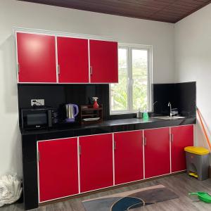 a kitchen with red cabinets and a microwave at Lotus Luxury Stays in Nanu Oya +8 photos