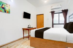 una camera da letto con un letto, una scrivania e una televisione di Collection O Candolim Beach Formerly Poornima Place a Candolim