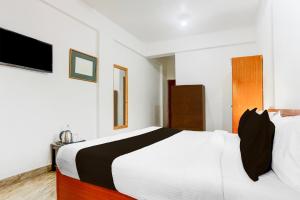 una camera da letto con un letto bianco e una televisione di Collection O Candolim Beach Formerly Poornima Place a Candolim Altre 23 foto