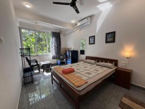 a bedroom with a bed and a table and a window at Studio Silent Grove R-6 by Mukund Sadan Arambol in Arambol +5 photos