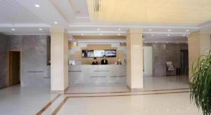 a lobby with two people standing at a counter in a building at GreenTree Inn Tibet Nyingchi City Biji Shenshan in Nyingchi
