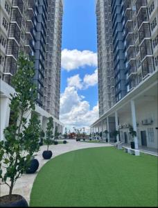 a grassy courtyard between two tall buildings at Sky28 - Sireh Residence in Kota Bharu