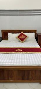 a bed with a wooden frame and white sheets at Nhà Nghỉ Phát Thành in Trà Vinh