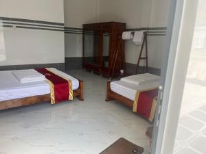 a room with two beds and a door to a room at Nhà Nghỉ Phát Thành in Trà Vinh