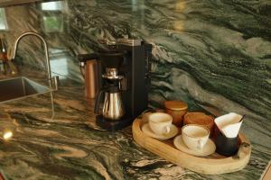 a counter with a coffee maker and cups on a tray at Buenadumo Jeju Tennis Holiday Villa in Sinch'ang-ni