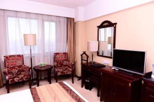 una camera d'albergo con televisore e una camera da letto di Heilongjiang Kunlun Hotel a Harbin