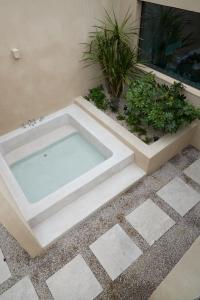 a hot tub in the middle of a patio with plants at Buenadumo Jeju Tennis Holiday Villa in Sinch'ang-ni