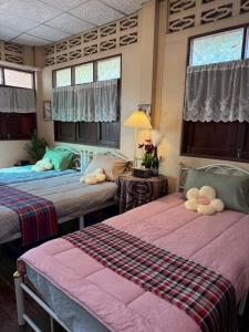 a bedroom with two beds with stuffed animals on them at บ้านสวนชายน้ำ โฮมสเตย์ อัมพวา in Ban Nong Chaeng