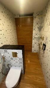 een badkamer met een toilet en een houten vloer bij The White Castle Hotel in Mysore