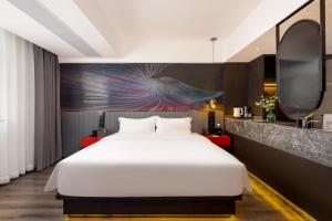a bedroom with a bed and a painting on the wall at Landwise in Haikou +50 photos