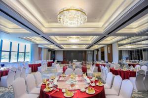 a banquet hall with tables and white chairs and a chandelier at Hampton by Hilton Zhuhai Doumen in Zhuhai