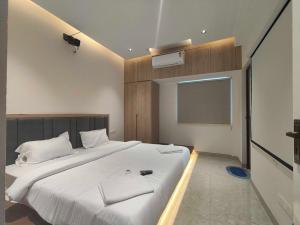 ein Schlafzimmer mit einem großen weißen Bett und einem Flachbildfernseher in der Unterkunft Townhouse Svb Tech Park Kalapatti Formerly RG Stays in Coimbatore (Peelamedu)