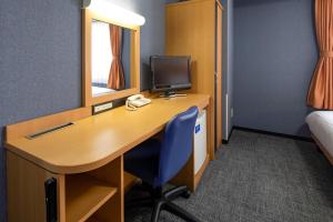 a room with a desk with a computer and a bed at Comfort Hotel Niigata in Niigata