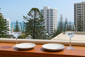 a table with two white plates and two wine glasses at Snapper Rocks Ocean view Retreat in Coolangatta