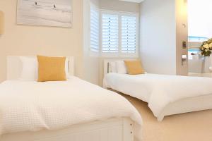 a white bedroom with two beds and a window at Snapper Rocks Ocean view Retreat in Coolangatta